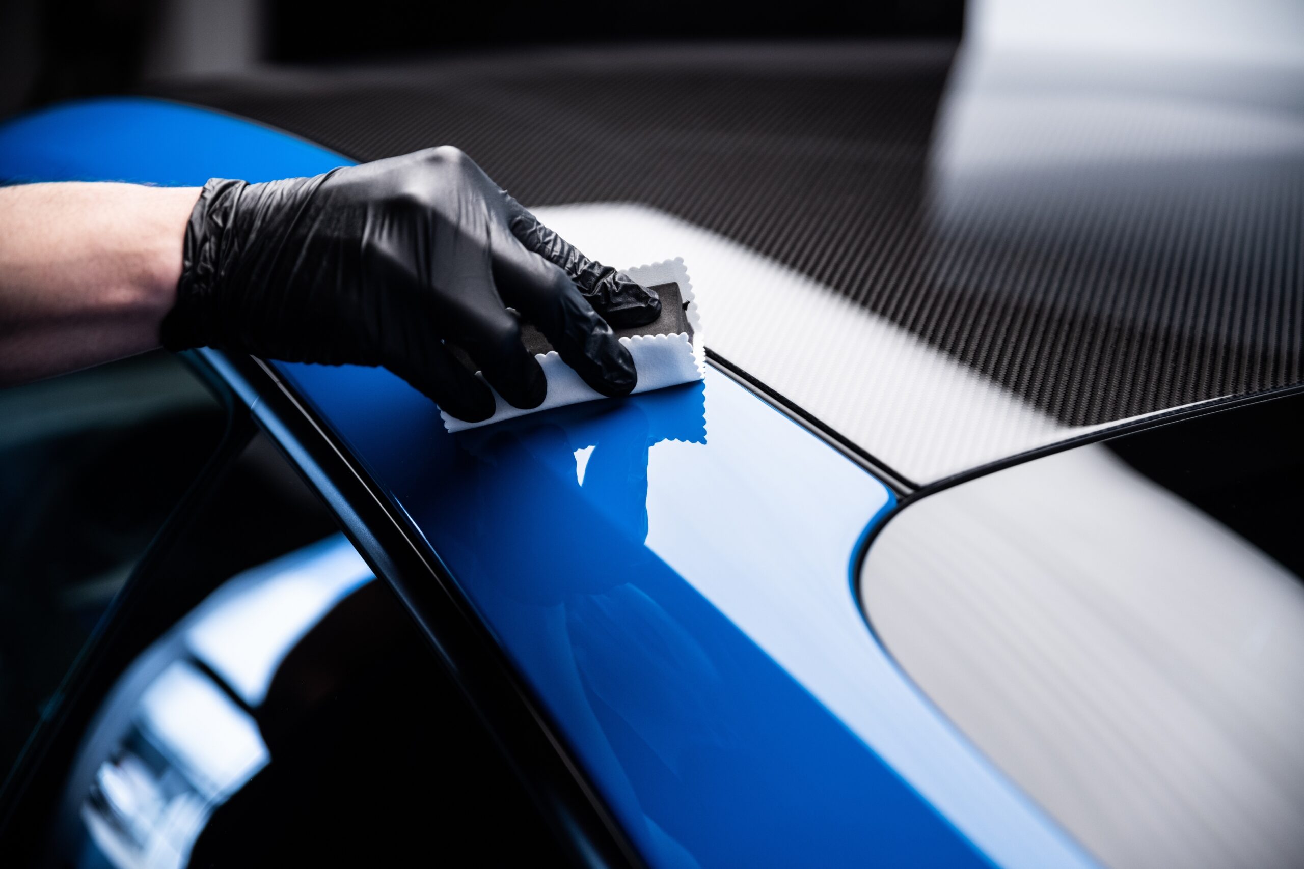 Car cash or car detailing studio worker applying graphene or ceramic coating